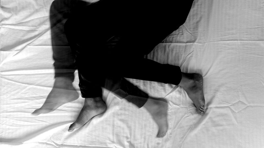 multiple exposure black and white photo, suggesting moving legs in a bed