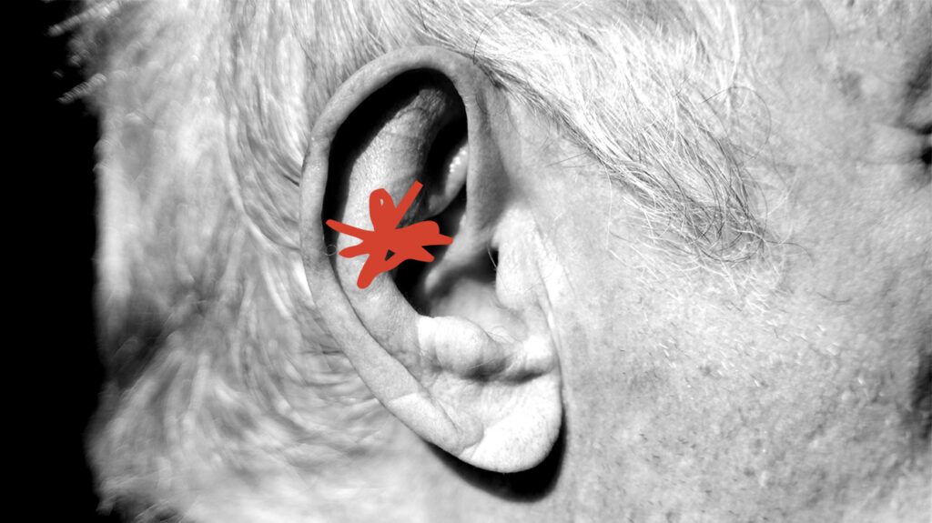 black and white photo of older man's ear marked with red asterisk