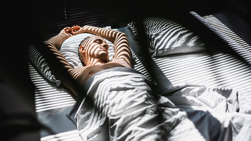 하얀 이불을 덮고 침대에 잠든 백인 남성