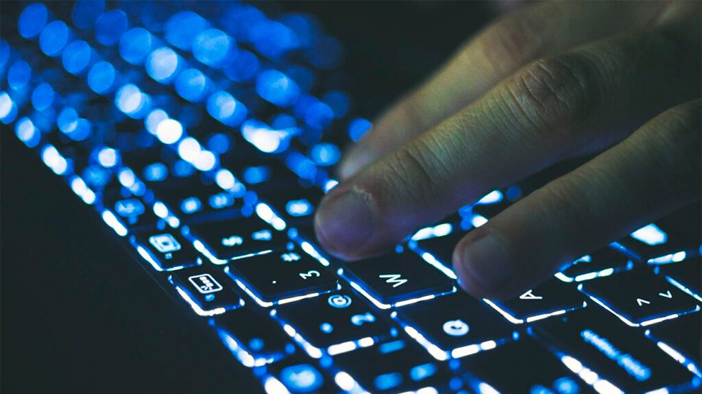 A person's hand typing on a keyboard.