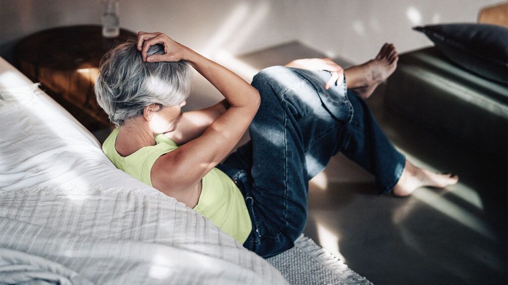 older white woman seen from behind, holding her head