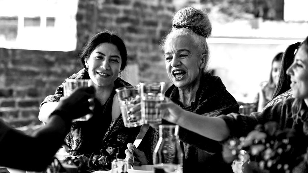 A group of women toasting drinks of water at a table, representing the Dry January practice of drinking no alcohol