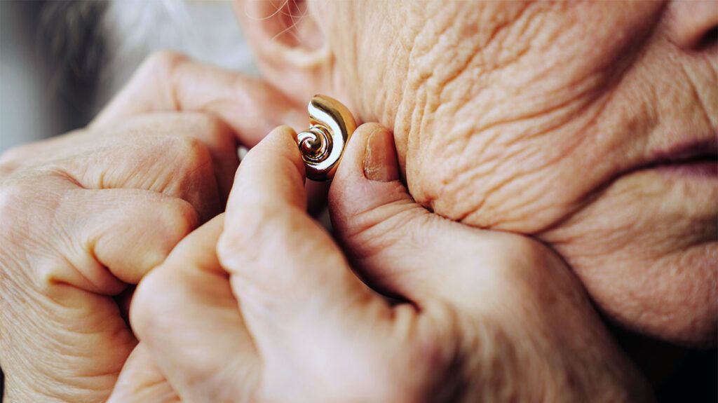 closeup of older white woman fastening gold earring