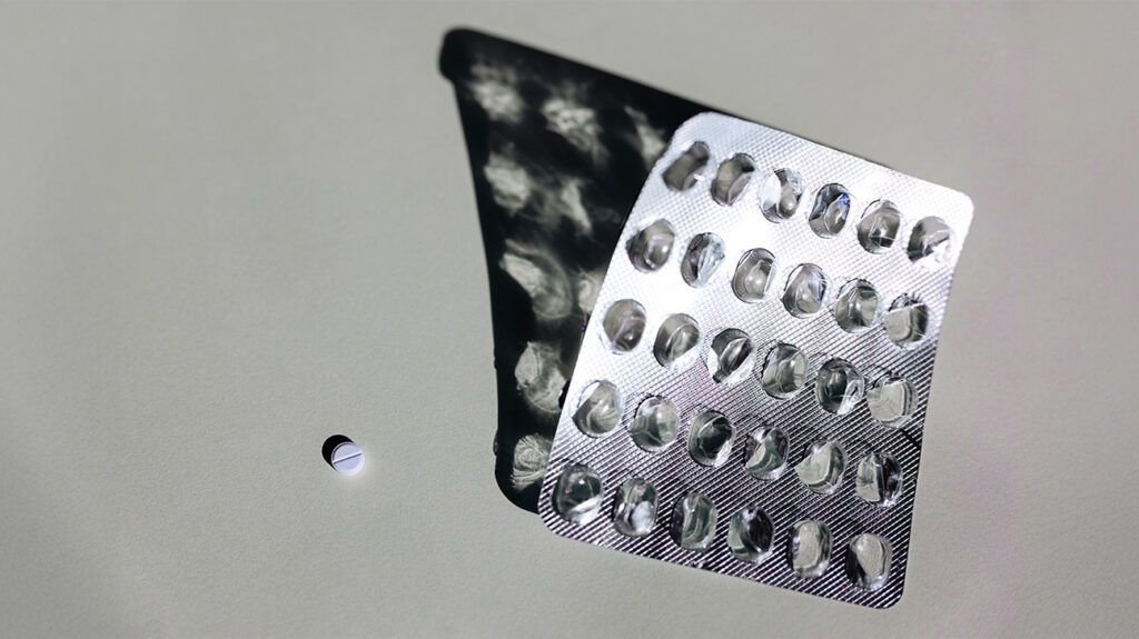 A pill sits next to an empty blister pack of levetiracetam