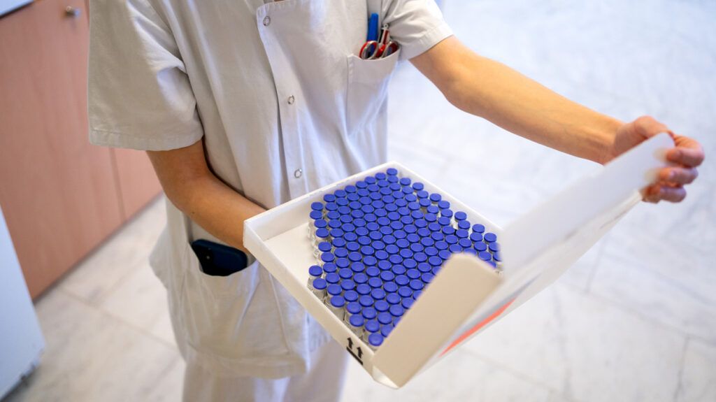 nurse holding box full of vaccine doses