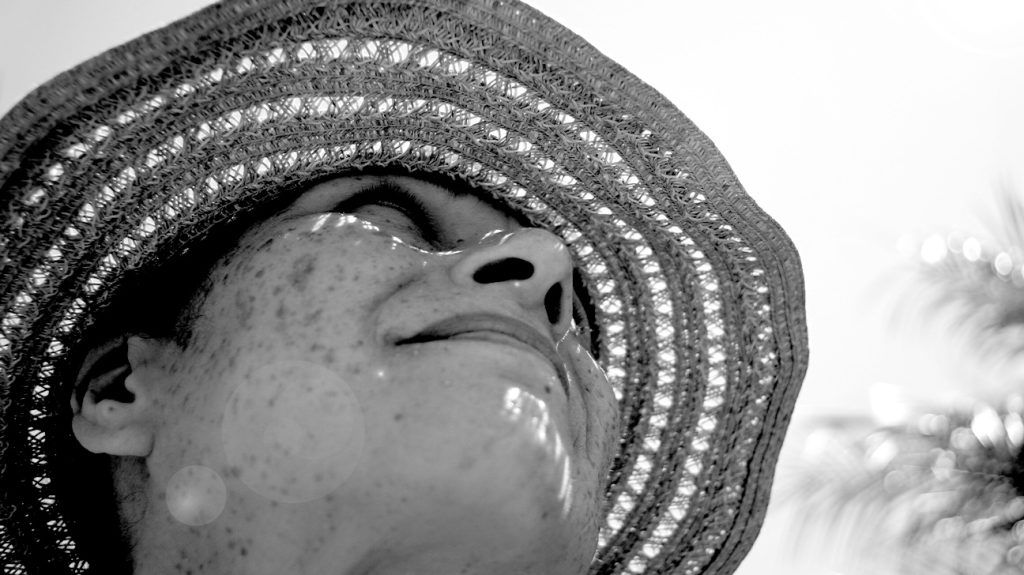 black and white close-up portrait of older woman wearing straw hat