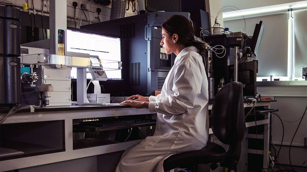 A laboratory worker looking at a screen.