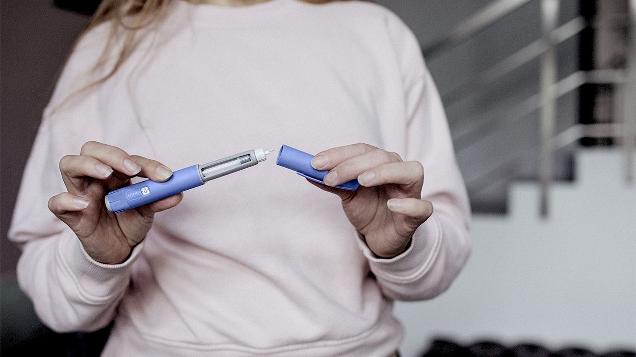 Person holding a GLP-1 syringe, representing new research linking Ozempic and Wegovy to lower cancer risk
