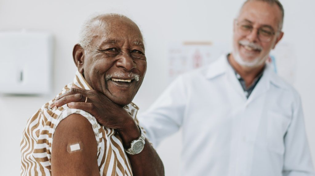 An older adult with a small bandage on their upper arm after a vaccine.