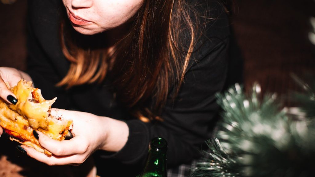 photo of woman eating a slice of pizza in the evening