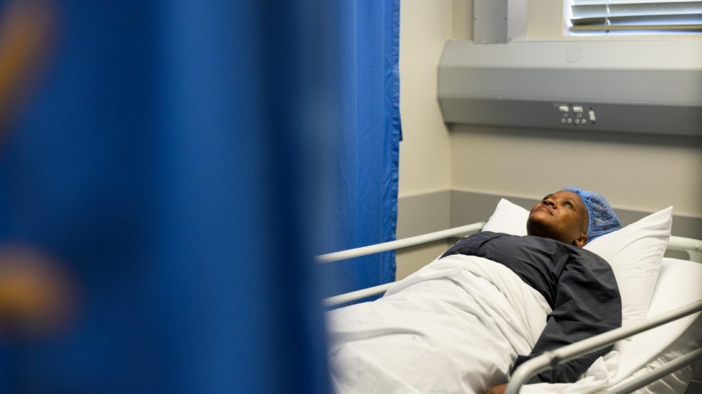 Black patient lying in hospital bed awaiting treatment