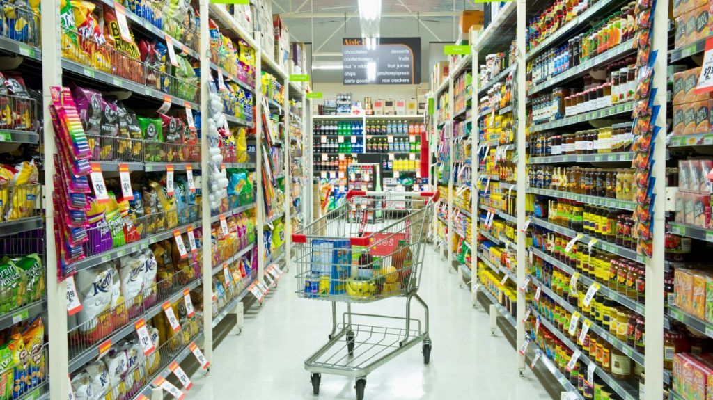A shopping cart in a grocery store aisle.