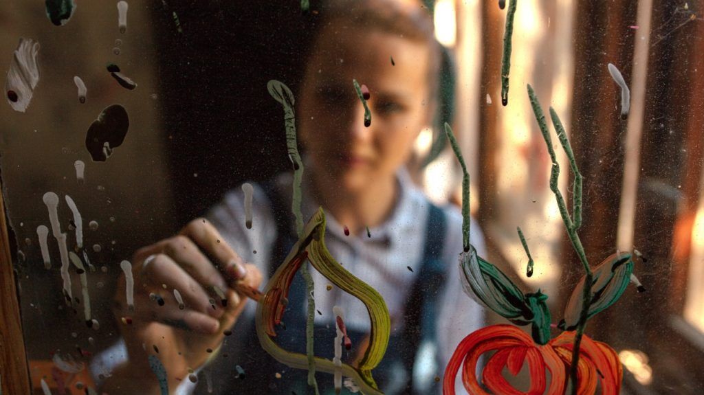 young person painting on glass surface