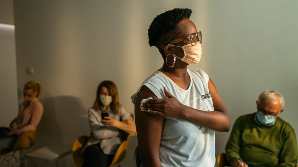 Black person standing in waiting room following COVID-19 vaccination