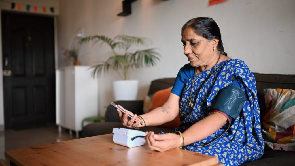 Older Indian woman in blue sari measuring her blood pressure