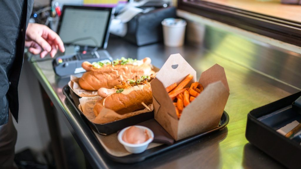 two subs and a bag of fries on a tray