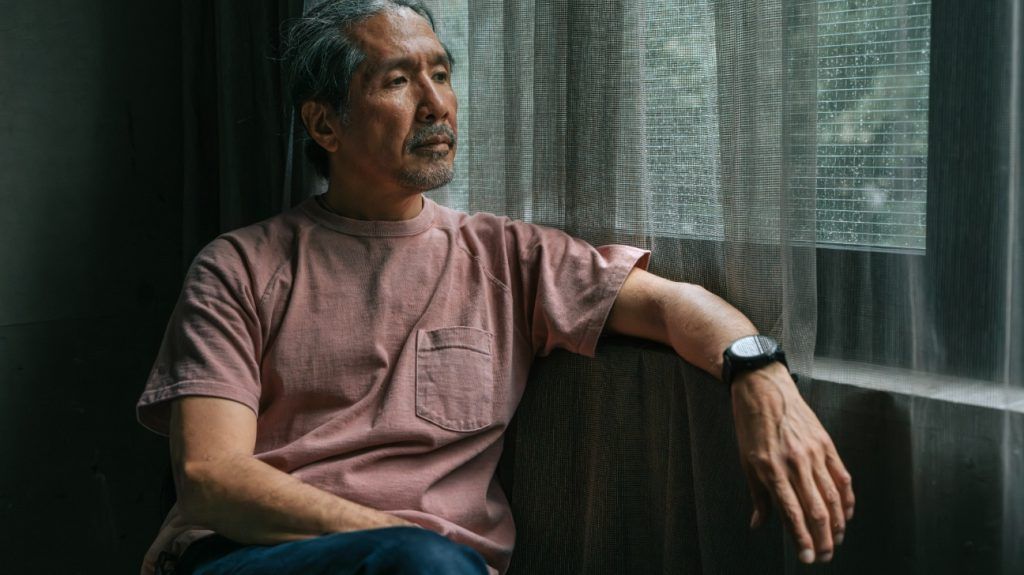 Pensive Mature Japanese Man Sitting by Rainy Window