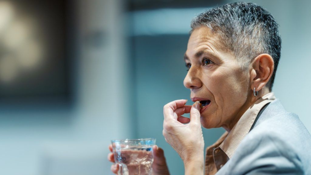 An older person taking a pill.