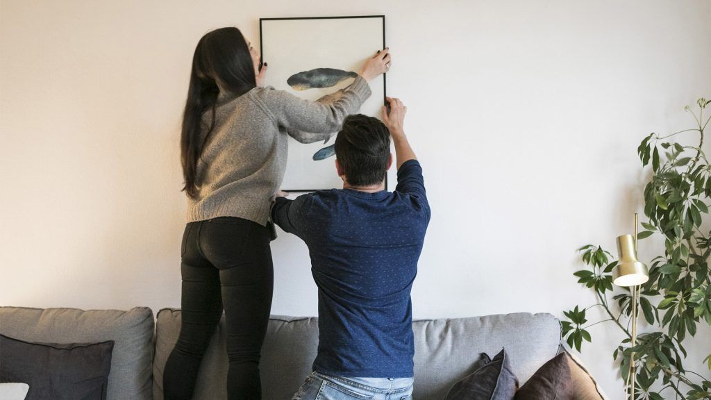 couple hanging a portrait on the wall