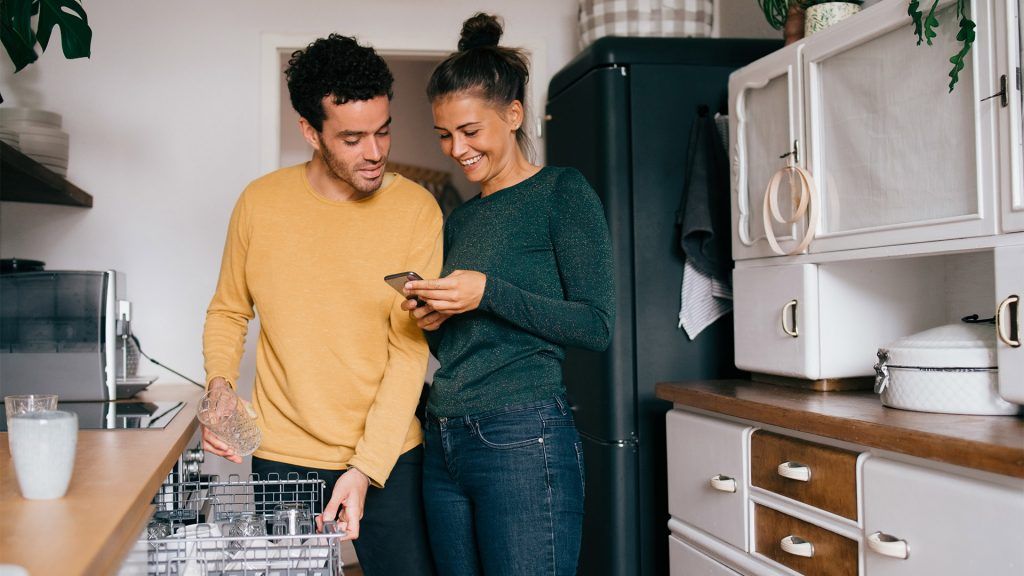 A couple in a kitchen looking at a smartphone