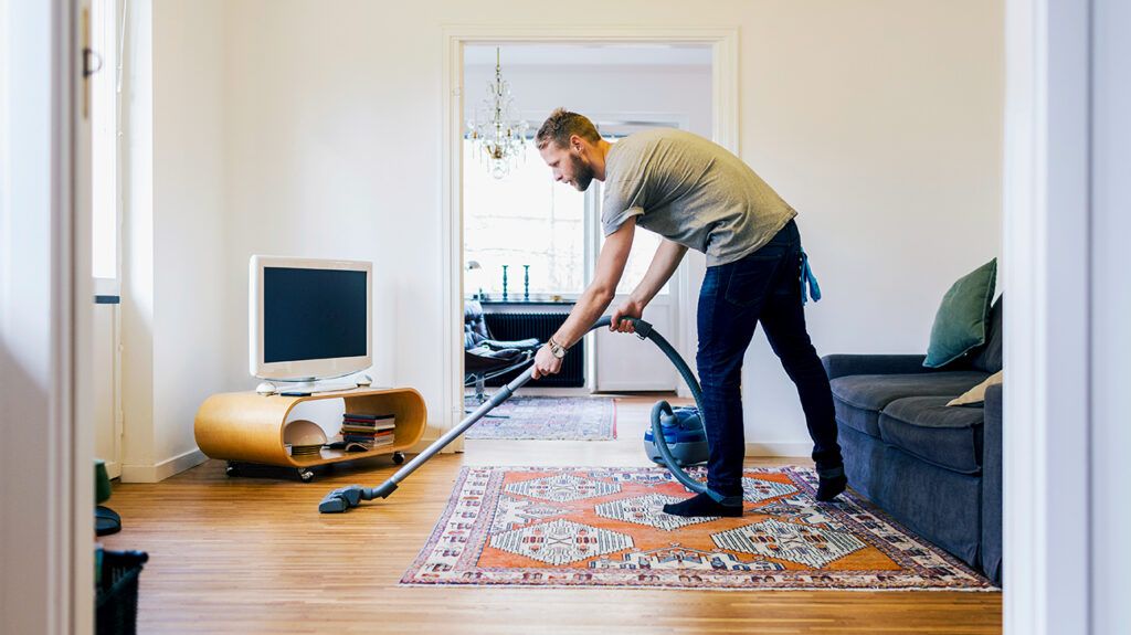 Man with ADHD cleaning his apartment while listening to an entertaining podcast