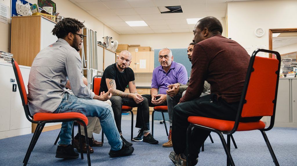 Men listening to eachother in group therapy