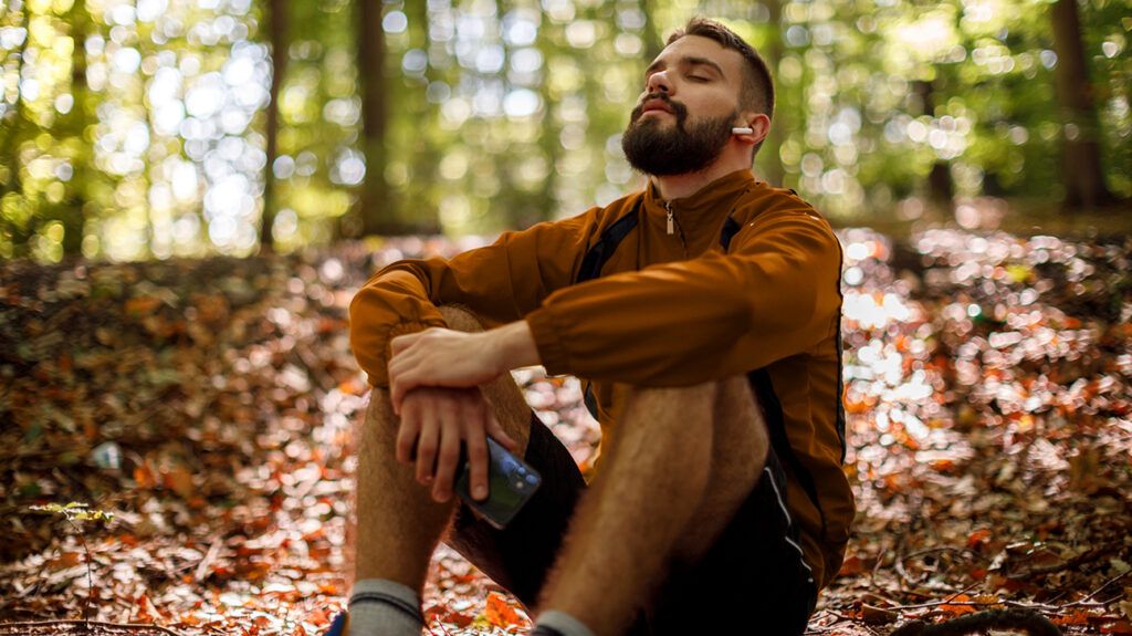 Man sitting in the forest trying to reconnect with himself after not feeling like himself lately