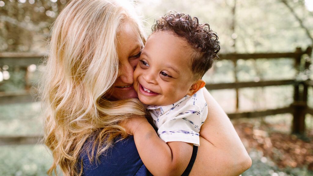 Mother hugging adopted son with down syndrome