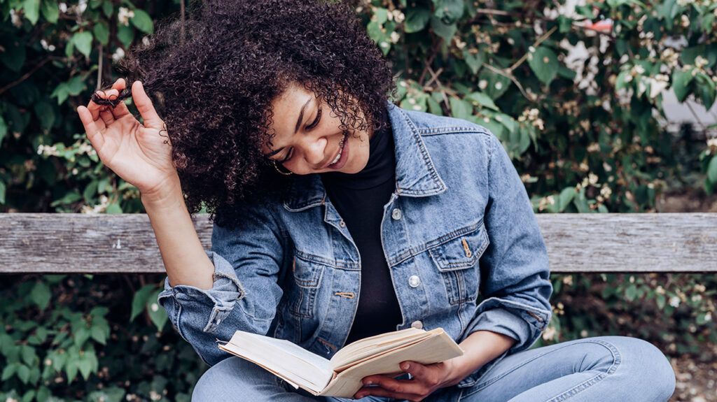 Woman reading mental health book on park bench