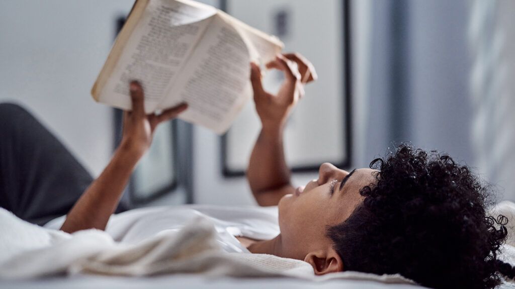 Person lying in bed reading a mindfulness book