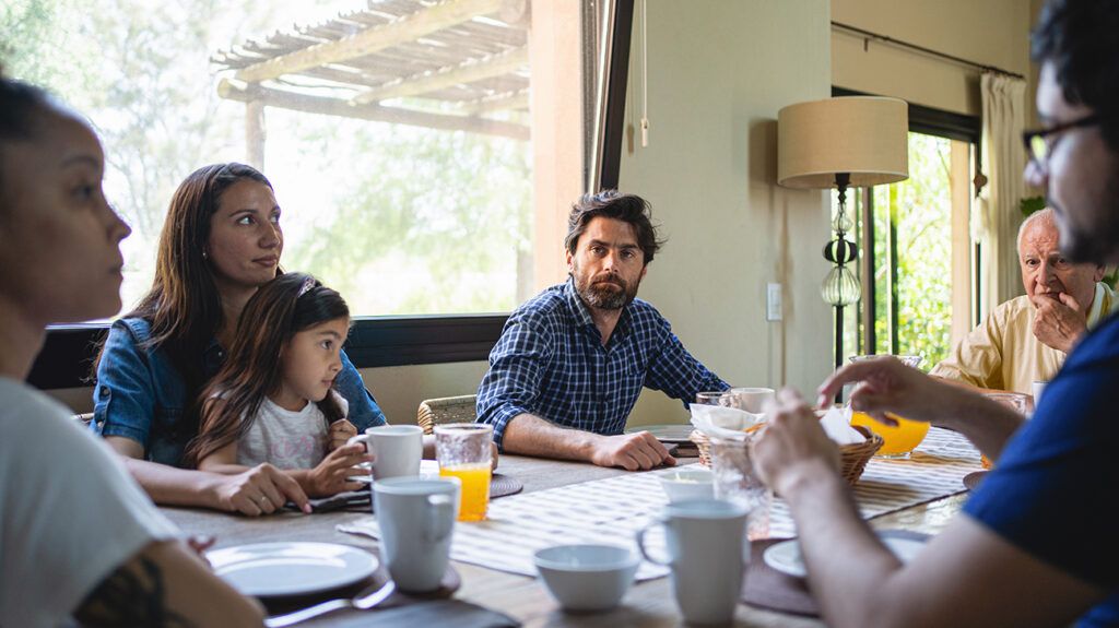 Family sitting at table together eating breakfast