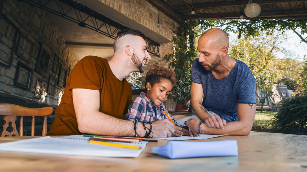Gay couple fathers helping daughter write
