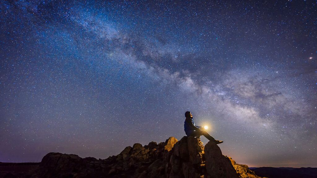 Man sitting on a rock under starry sky