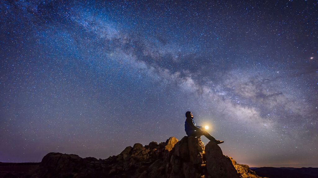 https://media.post.rvohealth.io/wp-content/uploads/sites/4/2021/09/man-sitting-under-milky-way-galaxy-night-sky-stars-1296x728-header-1024x575.jpg