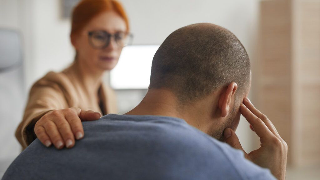 Therapist consoling a patient, with a pat on the back