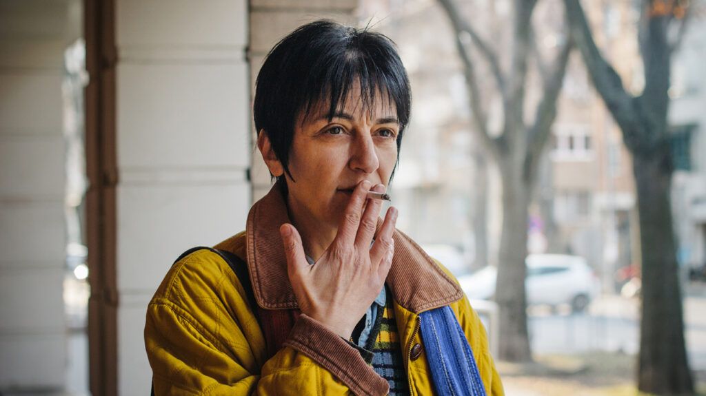 Older woman smoking cigarette outside 