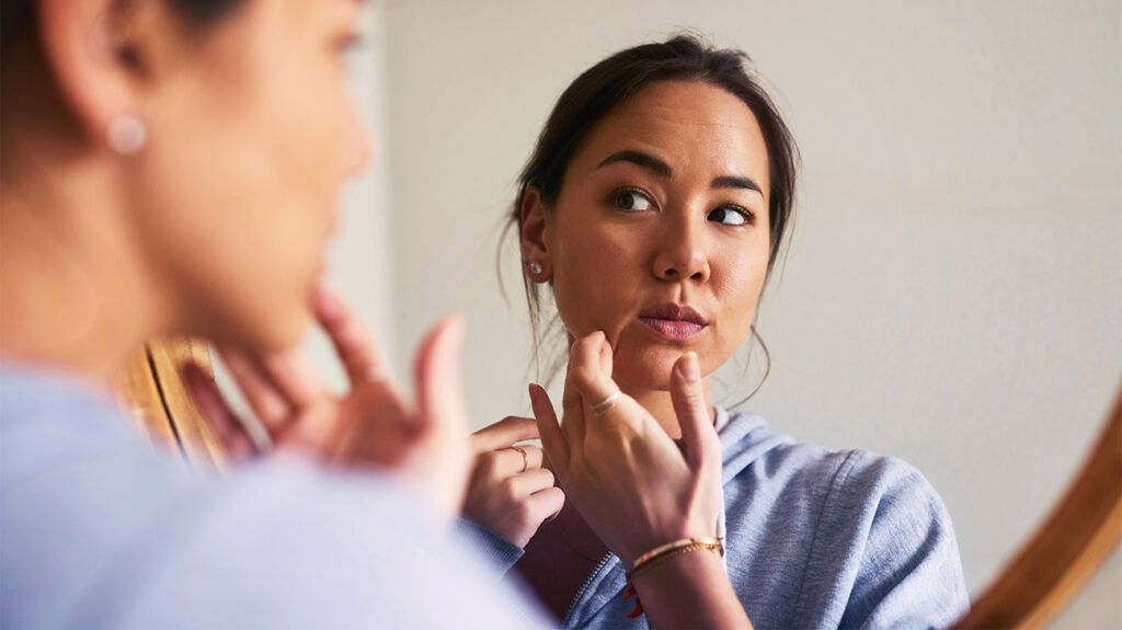 Woman looking at her skin in the mirror