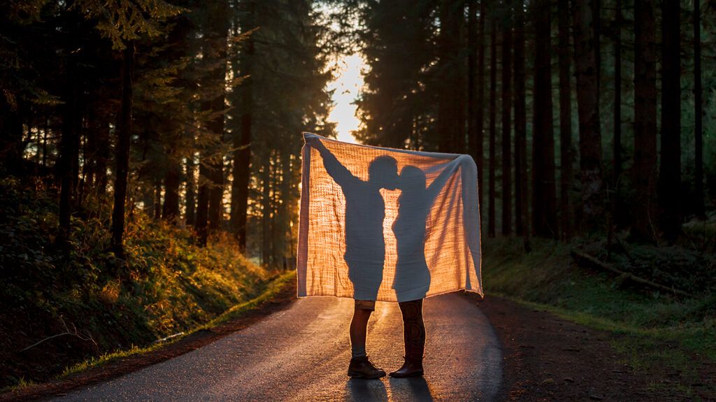 Silhouette of couple kissing behind blanket