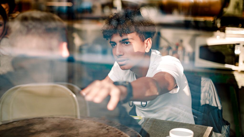 Teenage boy consoling friend through glass window