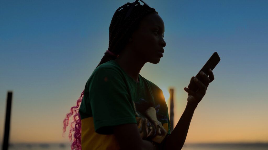 Woman looking at her phone at sunset by the ocean