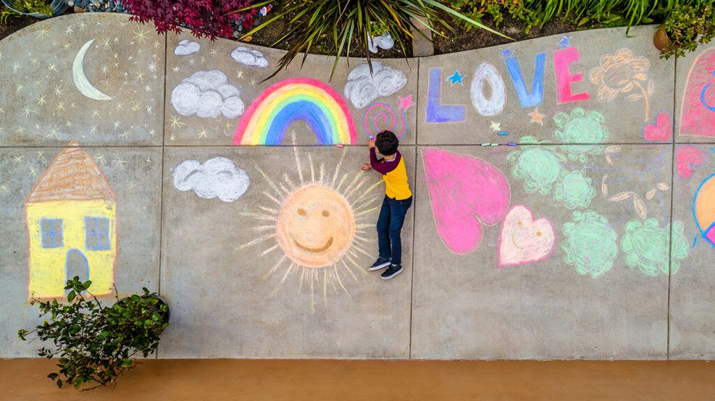 Aerial view above boy drawing with sidewalk chalk