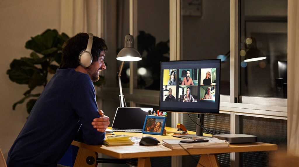 Man with headphones in front of his computer attending an online group therapy session