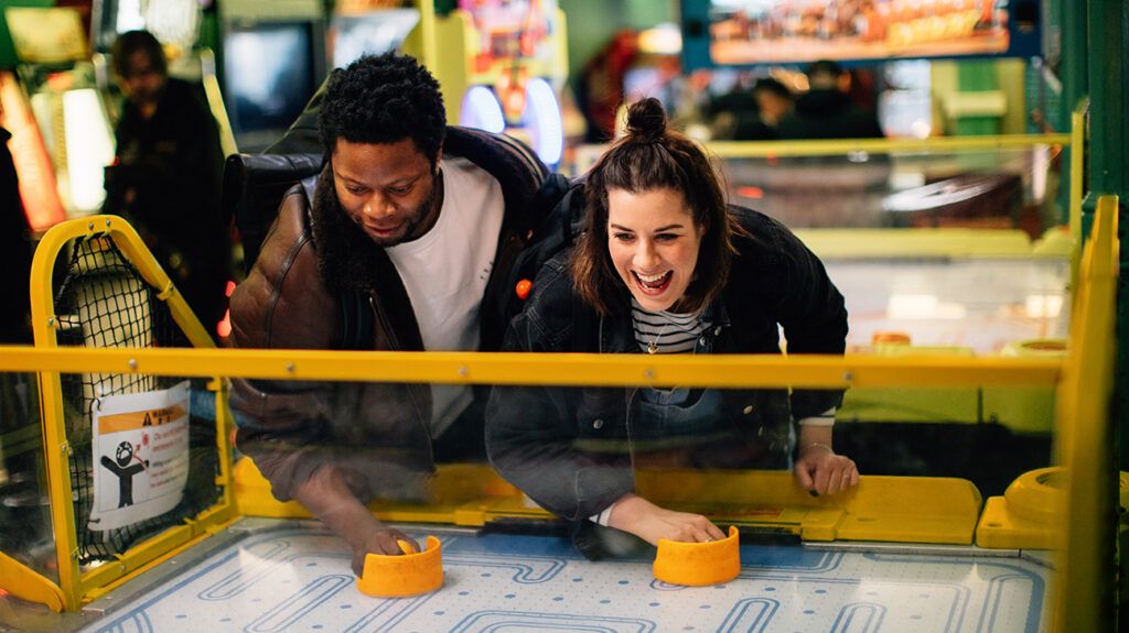 Couple playing air hockey in arcade