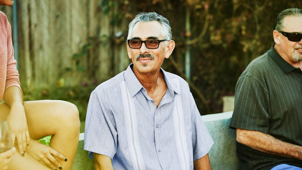 Smiling older Latinx man in a park or backyard