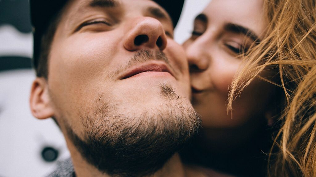 Alpha male being kissed by his alpha female parnter who wonders if they are compatible