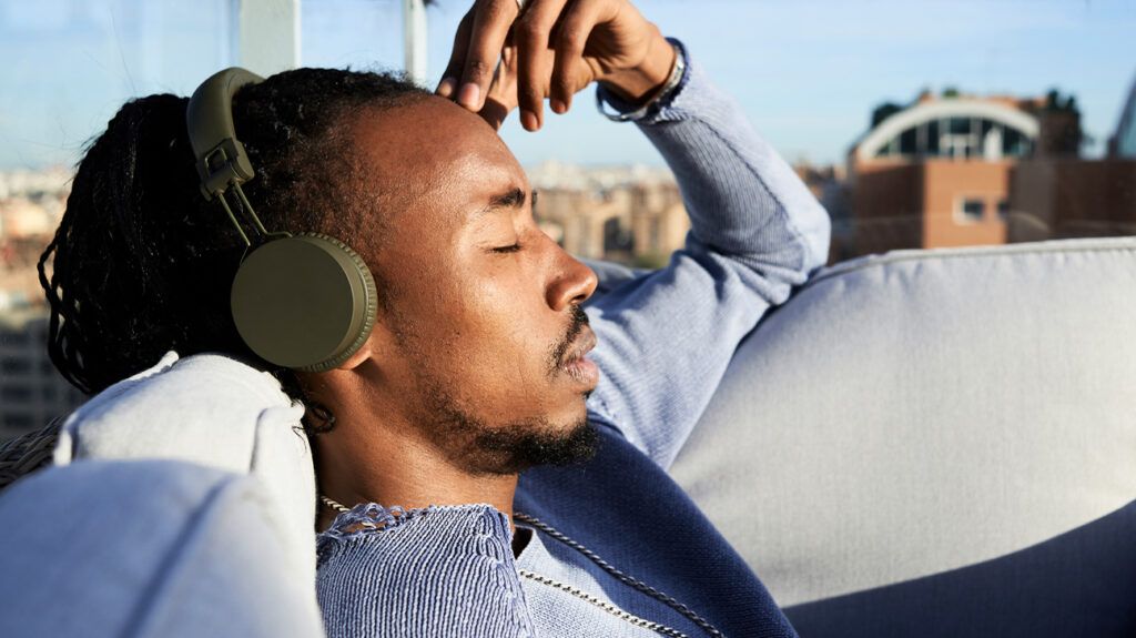 Man with his eyes closed listening to the Calm meditation app over headphones