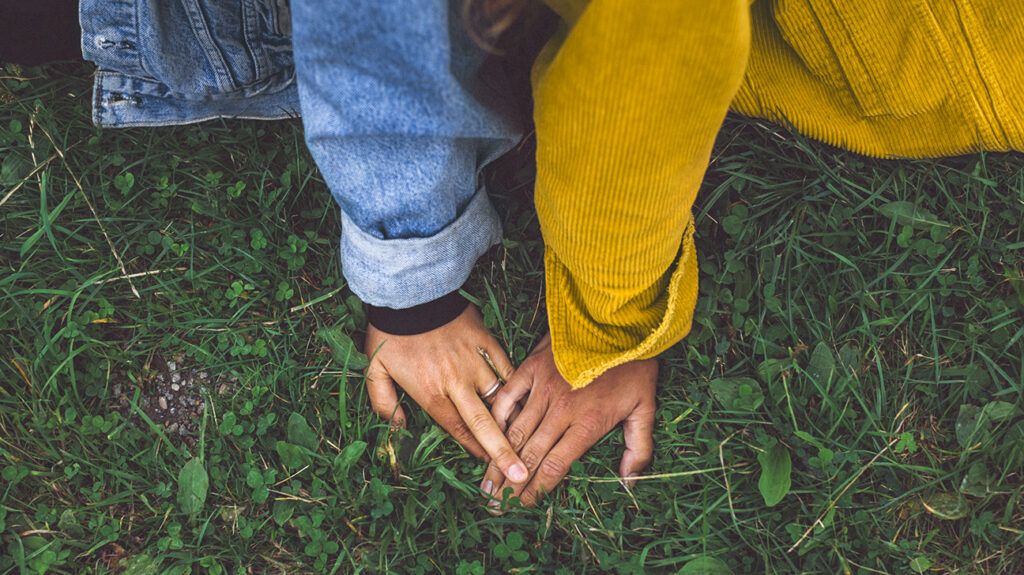 Couple holding hands sitting in grass