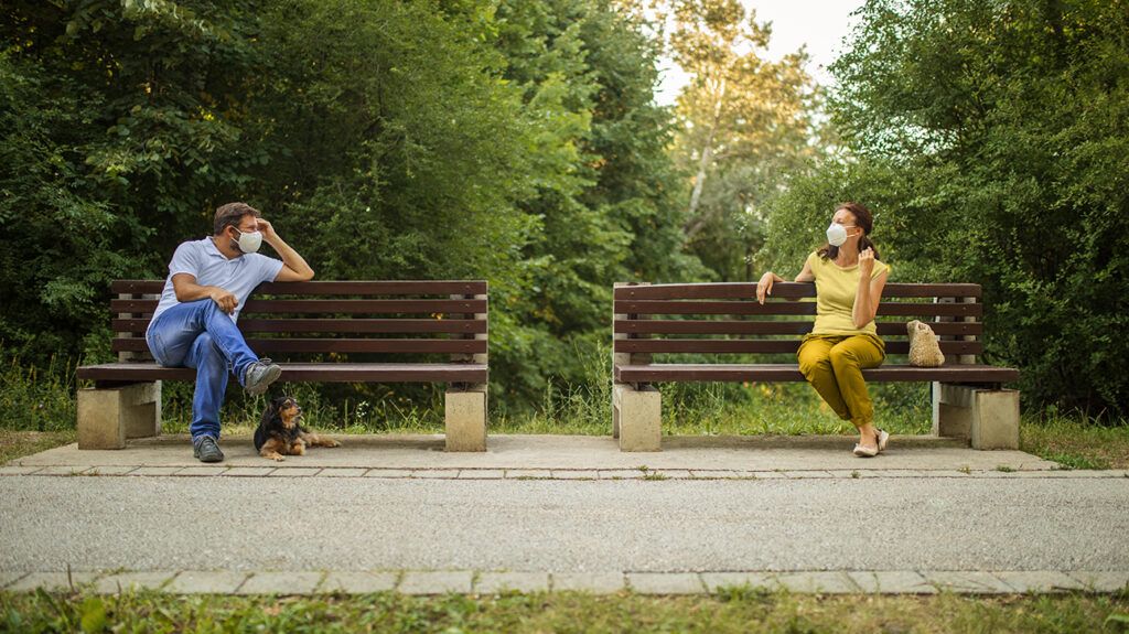 Two people meet masked and physically distant for a pandemic-friendly date