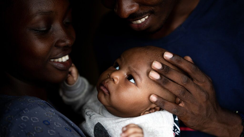 a man and woman holding their baby and smiling