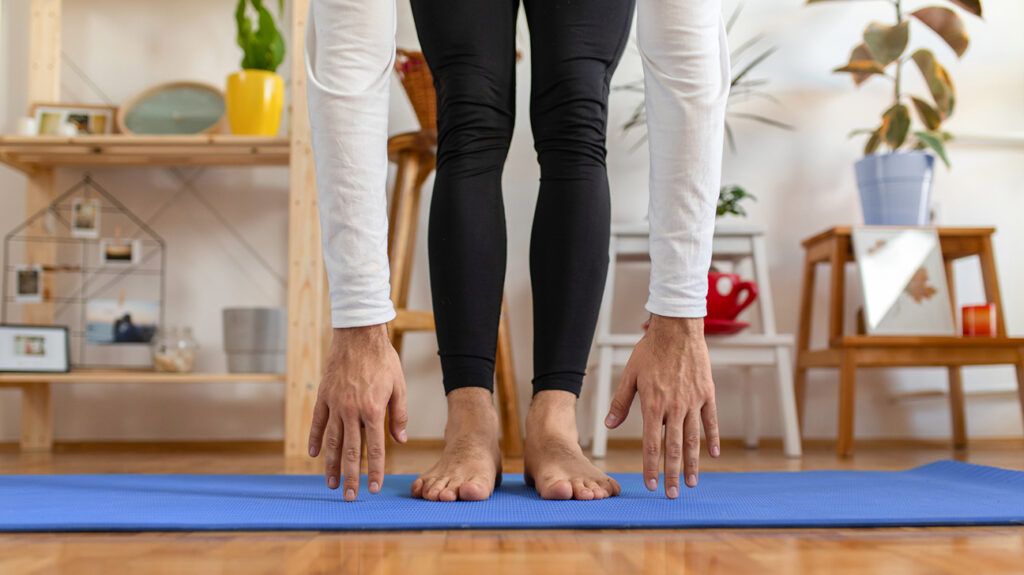 Man doing forward fold yoga pose on a mat